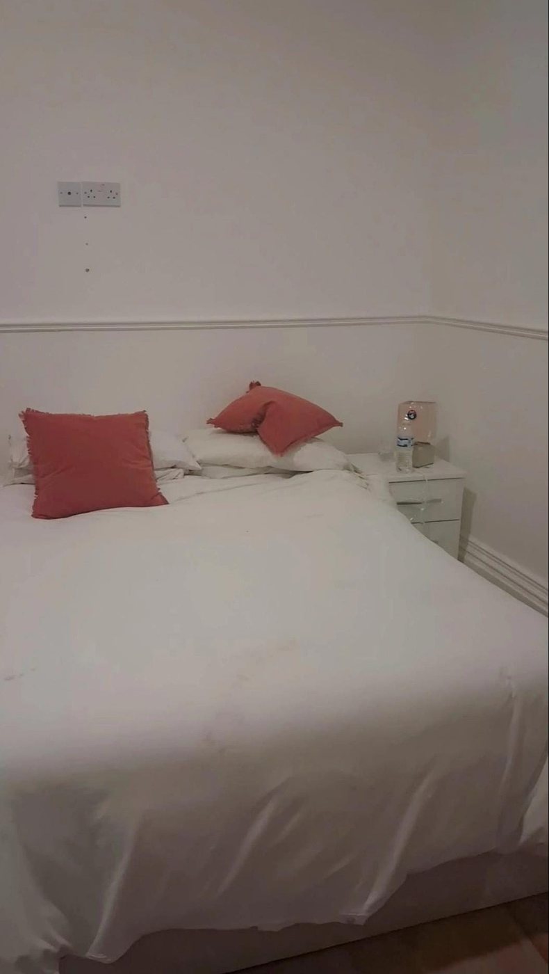 A furnished bedroom with bedside table and storage
