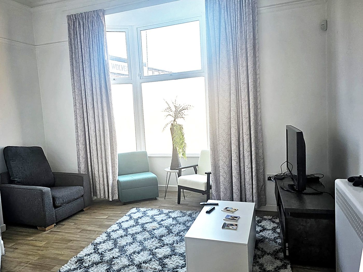 The bay-window lounge at Jubilee House, with seating, rug and television